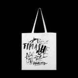 image of the front of a white tote bag. black scribble print covers the tote