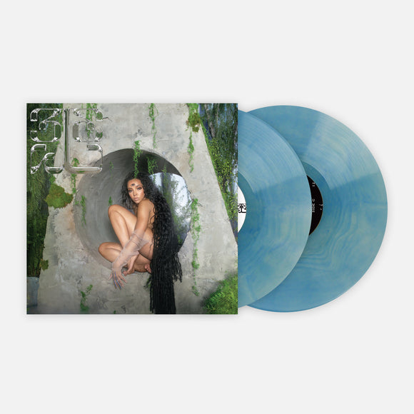 image of a double vinyl record, that is seafoam blue, coming out of the sleeve on the right of the album cover on the left of Tinashe's 333 album. Tinashe sits inside of a grey circle with green streaks. she has long dark hair and a third eye in the center of her forehead. the top left features the grey 333 logo.