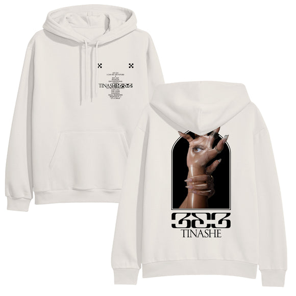Image of the front and back of a bone colored hoodie against a white background. The left chest features two small black checkerboard designs. Below in black is the track listing to tinashe's album 
