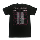 Image of the back of a black tshirt against a white background.   The back of the shirt in white dotted text reads "tinashe". Below this in white text reads 2021 tour. Below this is an outline to the 333 logo in red, with the tour dates printed over top of it in white text.