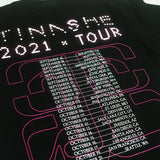 Close up image of the The back of the black shirt. across the top of it in white dotted text reads "tinashe". Below this in white text reads 2021 tour. Below this is an outline to the 333 logo in red, with the tour dates printed over top of it in white text.