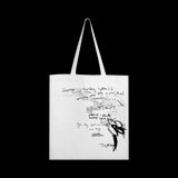 image of the back of a white tote bag. black scribble print covers the tote