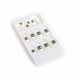Image of white fake nail stickers against a white background. The nails all feature the Tinashe 333 logo on the center of them in black. The logo is a 3 facing the right way, mirrored by a 3 facing the opposite way, connected to a large 3 that is sideways and across the bottom of the other two 3's, forming a square shaped logo.