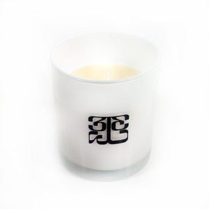 Image of a white/clear candle against a white background. The cylindrical candle holder is white/clear with a black 333 logo on it. The logo is a 3 facing the right way, mirrored by a 3 facing the opposite way, connected to a large 3 that is sideways and across the bottom of the other two 3's, forming a square shaped logo. the candle inside is white.
